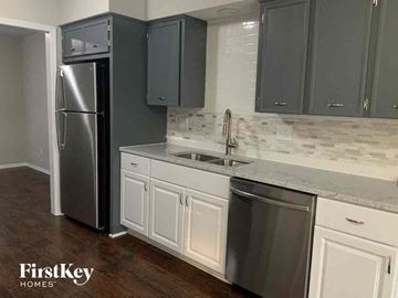 Independence house for rent - a kitchen with white cabinets and a stainless steel refrigerator