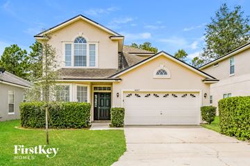 Orange Park house for rent - a beige house with a garage door and a lawn