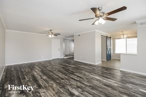Mesa house for rent - an empty living room with a ceiling fan and a door to a hallway
