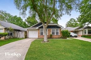 Houston house for rent - a brick house with a white garage door and a tree in the yard