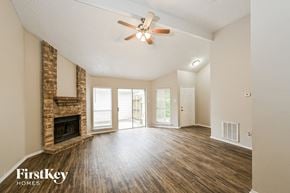 Houston house for rent - an empty living room with a fireplace and a ceiling fan