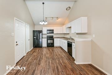 Houston house for rent - a kitchen with white cabinets and black appliances and wood flooring