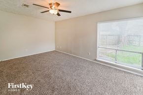 Houston house for rent - a bedroom with a large window and a ceiling fan