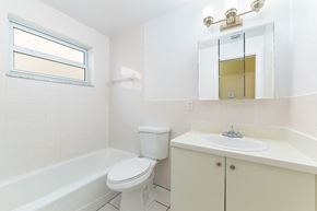 Hollywood apartment for rent - A white bathroom with a toilet, sink, and tub.