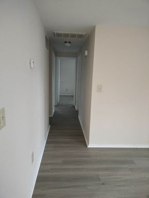 Kettering apartment for rent - a long hallway with white walls and wood floors and a door in the distance