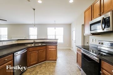 Fuquay-Varina house for rent - a kitchen with wooden cabinets and black counter tops and stainless steel appliances
