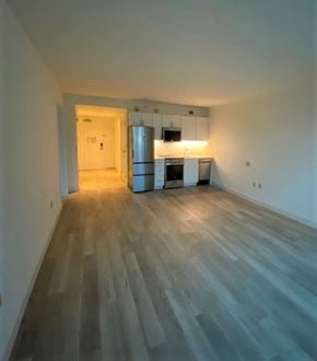 Atlantic City apartment for rent - A room with a kitchen in the background and a wooden floor.