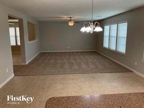 Katy house for rent - A spacious room with a rug on the floor and a chandelier hanging from the ceiling.