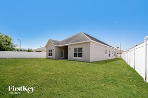 Kissimmee house for rent - A house with a white fence and a grassy yard.
