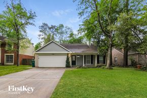 Spring house for rent - A house with a garage is surrounded by trees and grass.