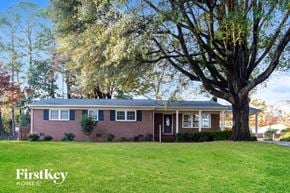 Gastonia house for rent - a red brick house with a large tree in the yard