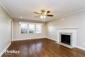 Gastonia house for rent - a living room with a fireplace and a ceiling fan