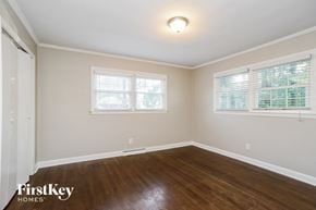 Gastonia house for rent - a bedroom with wood floors and white walls and two windows