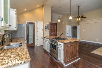 Denton house for rent - a kitchen with white cabinets and granite counter tops