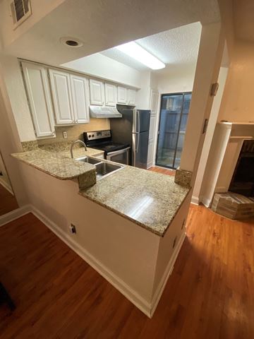 Lafayette house for rent - A kitchen with white cabinets and a granite countertop.