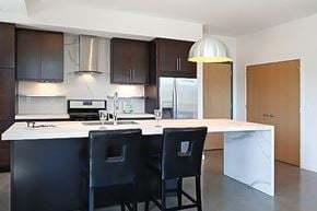 Minneapolis apartment for rent - A kitchen with a white island and black chairs.