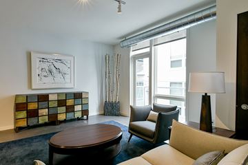 Minneapolis apartment for rent - A living room with a brown coffee table, a lamp, a chair, a sofa, and a painting on the wall.