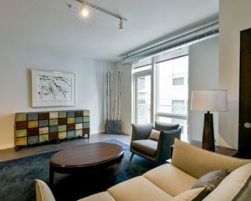 Minneapolis apartment for rent - A living room with a brown coffee table, beige couch, and a painting on the wall.