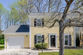 Charlotte house for rent - A yellow house with a black roof and a white garage door.