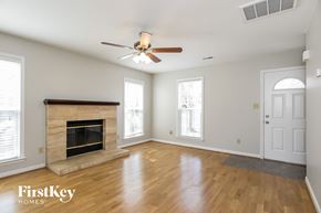 Charlotte house for rent - A spacious room with a fireplace and a ceiling fan.