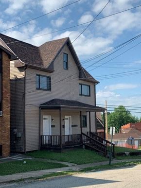 East Mckeesport apartment for rent - A house with a brown roof and a grey siding with a black railing.