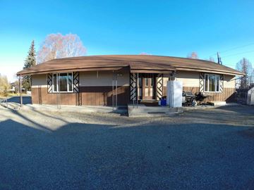 Fairbanks apartment for rent - A house with a brown roof and white trim is surrounded by a gravel driveway.