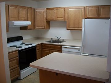 Fairbanks apartment for rent - A kitchen with wooden cabinets and a white refrigerator.