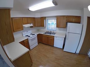 Fairbanks apartment for rent - A kitchen with white appliances and wooden cabinets.