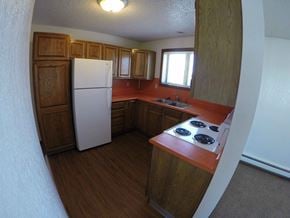 Fairbanks apartment for rent - A kitchen with a white fridge and wooden cabinets.