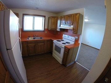 Fairbanks apartment for rent - A kitchen with wooden cabinets and a white stove top oven.