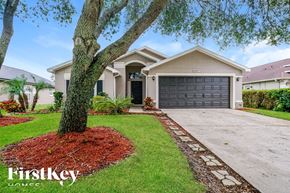 Wesley Chapel house for rent - a home with a black garage door and a tree
