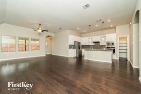 Fort Worth house for rent - an empty living room with a kitchen and a ceiling fan