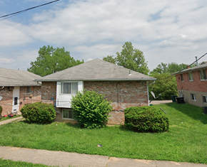 Cincinnati apartment for rent - A house with a grey roof and a white window surrounded by green bushes.