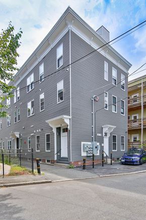 Cambridge apartment for rent - a grey apartment building with a blue car parked in front of it