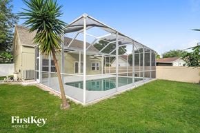 Riverview house for rent - A pool enclosed by a glass wall with a palm tree in front.