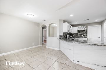 Lehigh Acres house for rent - a large white kitchen with a marble counter top