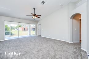 Lehigh Acres house for rent - A spacious room with a ceiling fan and carpeted floor.