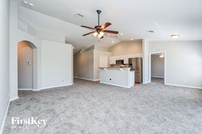 Lehigh Acres house for rent - A spacious living room with a ceiling fan and a kitchen area in the background.