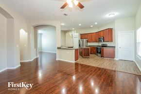 Orange Park house for rent - an empty living room and kitchen with wood flooring and a ceiling fan