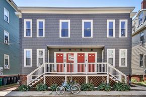 Cambridge apartment for rent - A grey house with a red door and a bicycle in front.