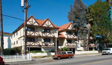 Van Nuys apartment for rent - A white picket fence in front of a brown and white building.