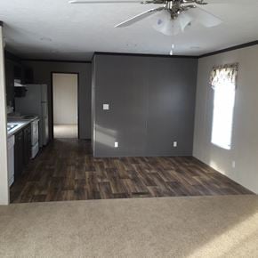 Houston apartment for rent - an empty living room with a kitchen and a ceiling fan