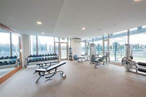 Vancouver apartment for rent - A spacious gym with a variety of equipment and a view of trees outside the windows.