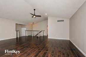 Lake Saint Louis house for rent - A spacious room with wooden floors and a ceiling fan.