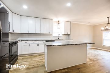 Lenexa house for rent - A kitchen with white cabinets and a marble countertop.
