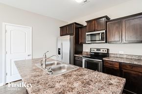 Midland house for rent - a kitchen with brown cabinets and granite counter tops and a sink