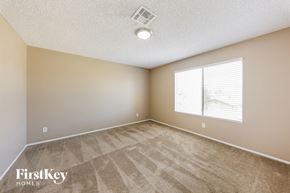 Peoria house for rent - an empty bedroom with a large window and carpeted flooring