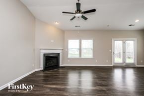 Mooresville house for rent - A spacious room with a fireplace and a ceiling fan.