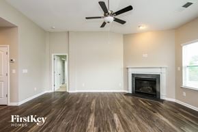 Mooresville house for rent - A spacious room with a fireplace and a ceiling fan.