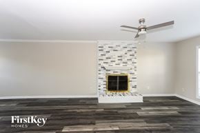 Charlotte house for rent - the living room of a new home with a brick fireplace and a ceiling fan